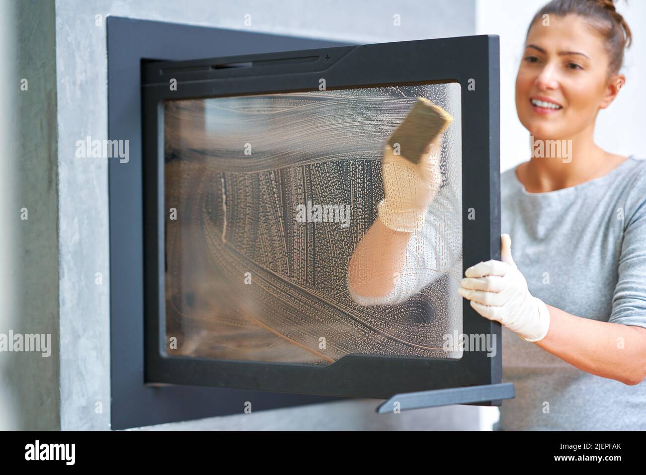 Picture of young woman cleaning fireplace glass doors Stock Photo Alamy