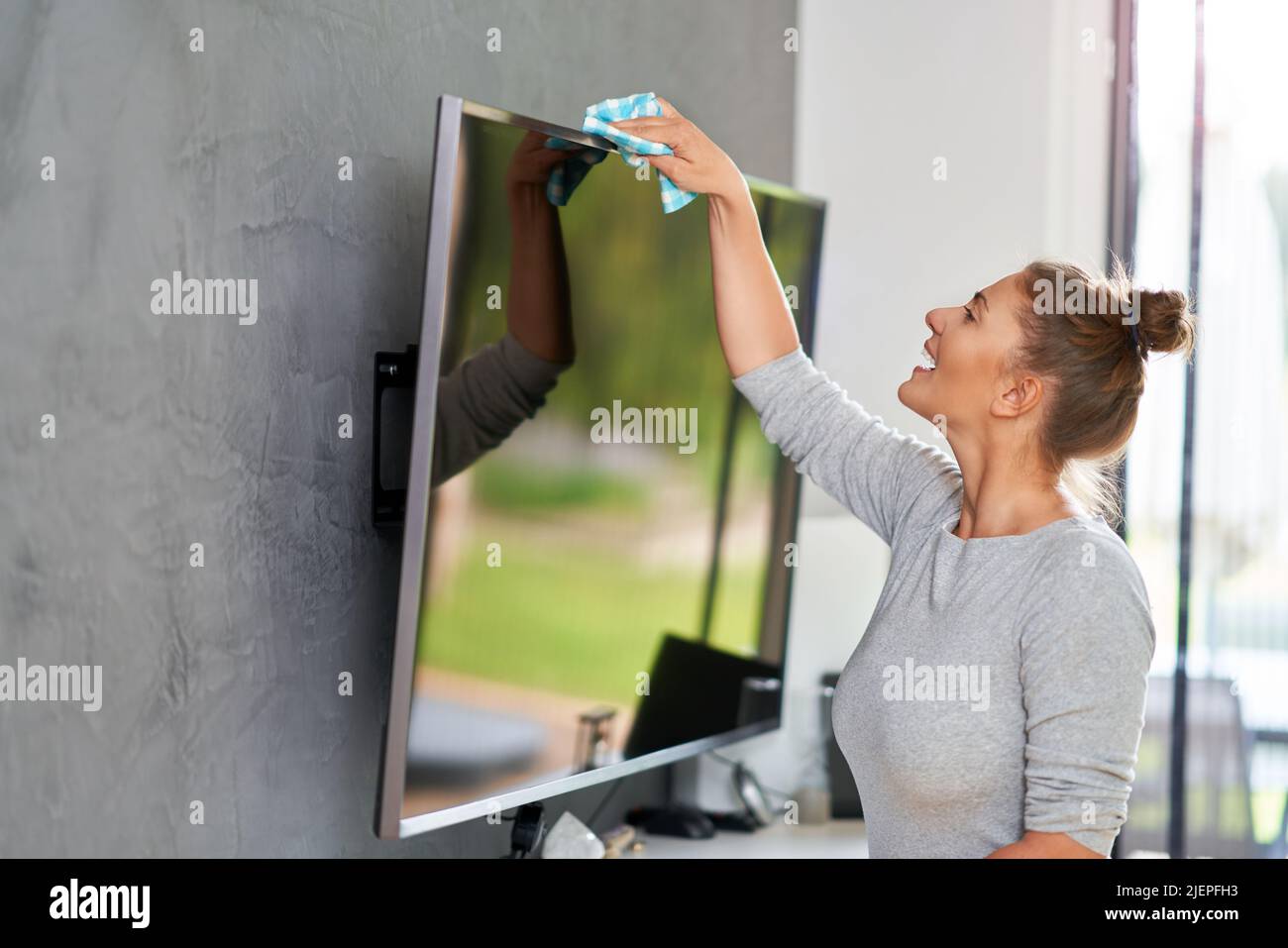Picture of young woman cleaning tv screen Stock Photo Alamy
