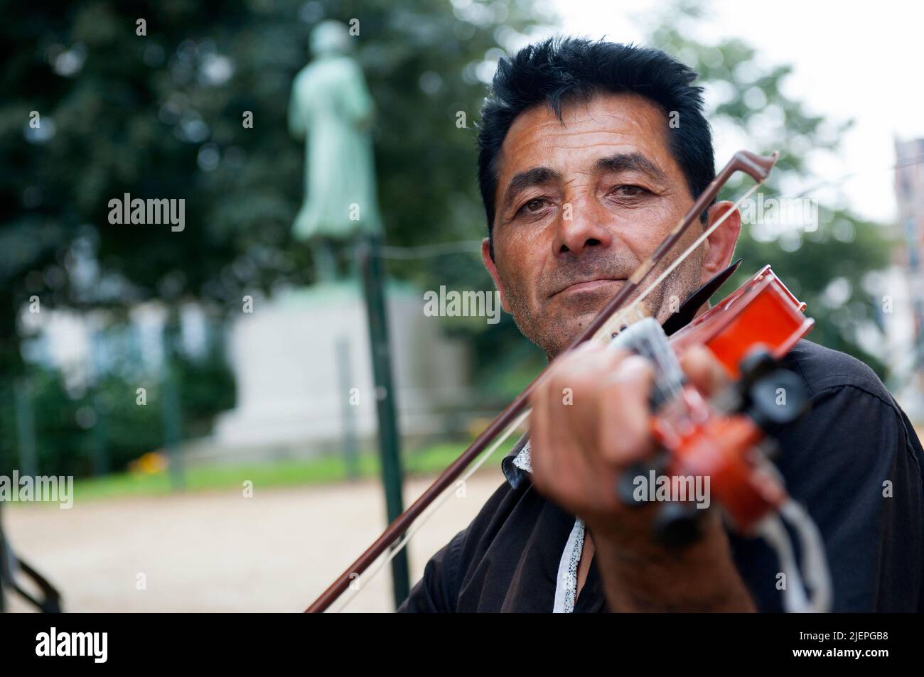 Een Zuid-Europese vioolspeler oefent zich in het Brusselse Leopoldspark. Stock Photo