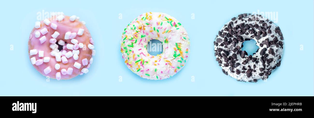 Three tasty donuts on light blue background. Top view Stock Photo