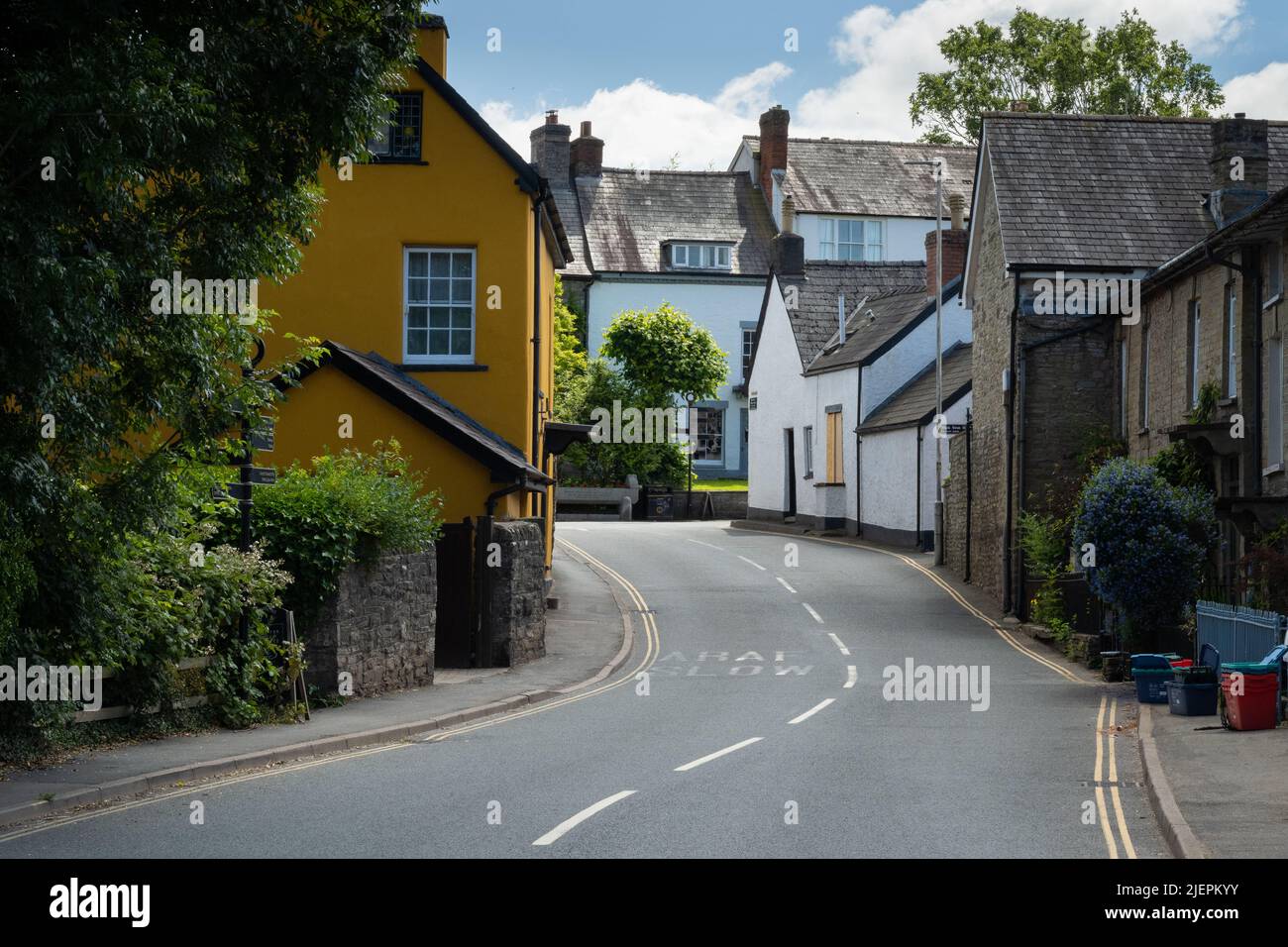 Yellow house with white windows and old houses by a road at HayonWye