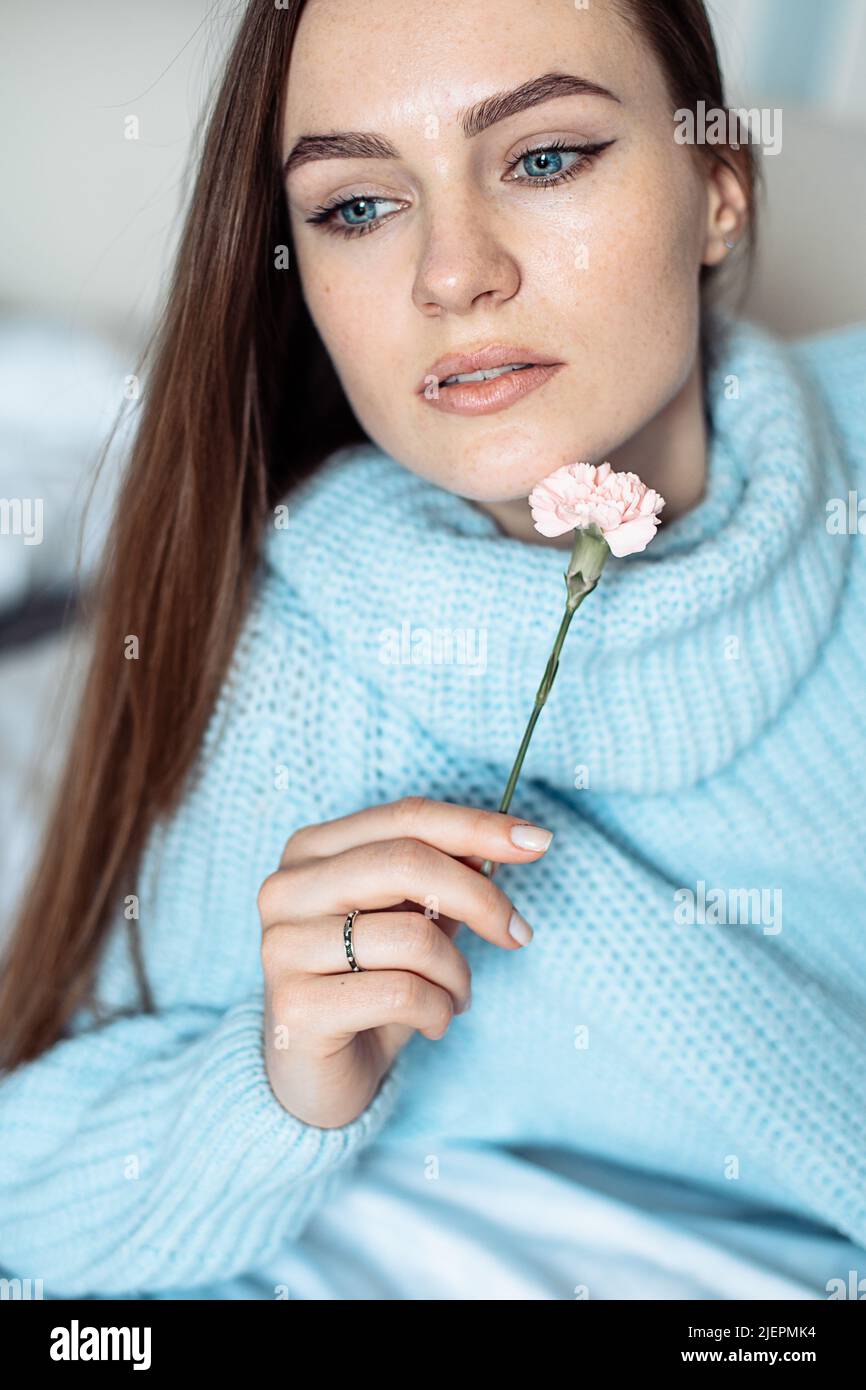 Romantic portrait of cute woman holding flower near face with tenderness, closeup portrait, natural beauty, skin care  Stock Photo