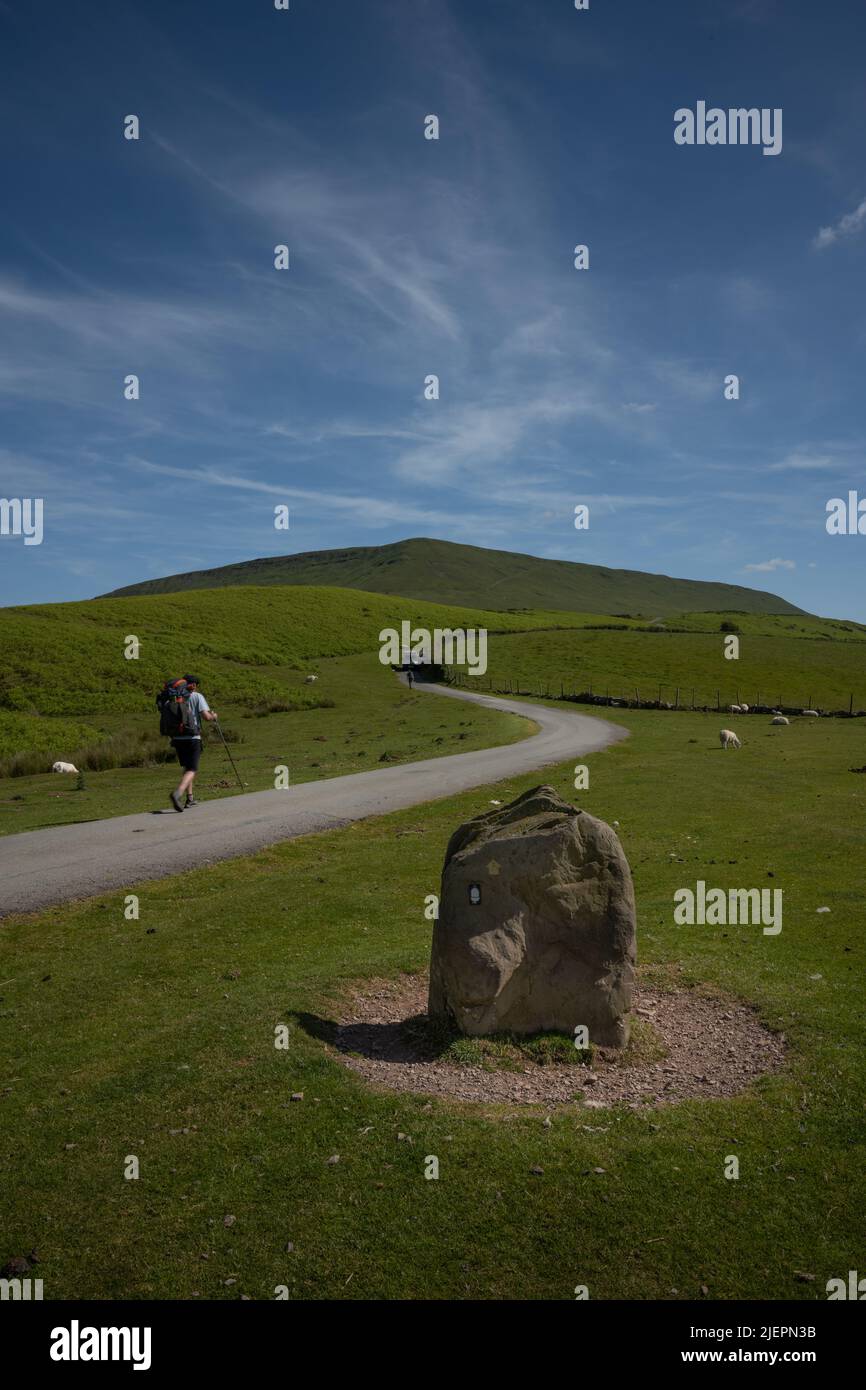 Stone pointing at Offa's Dyke Path with hikers on the road leading to