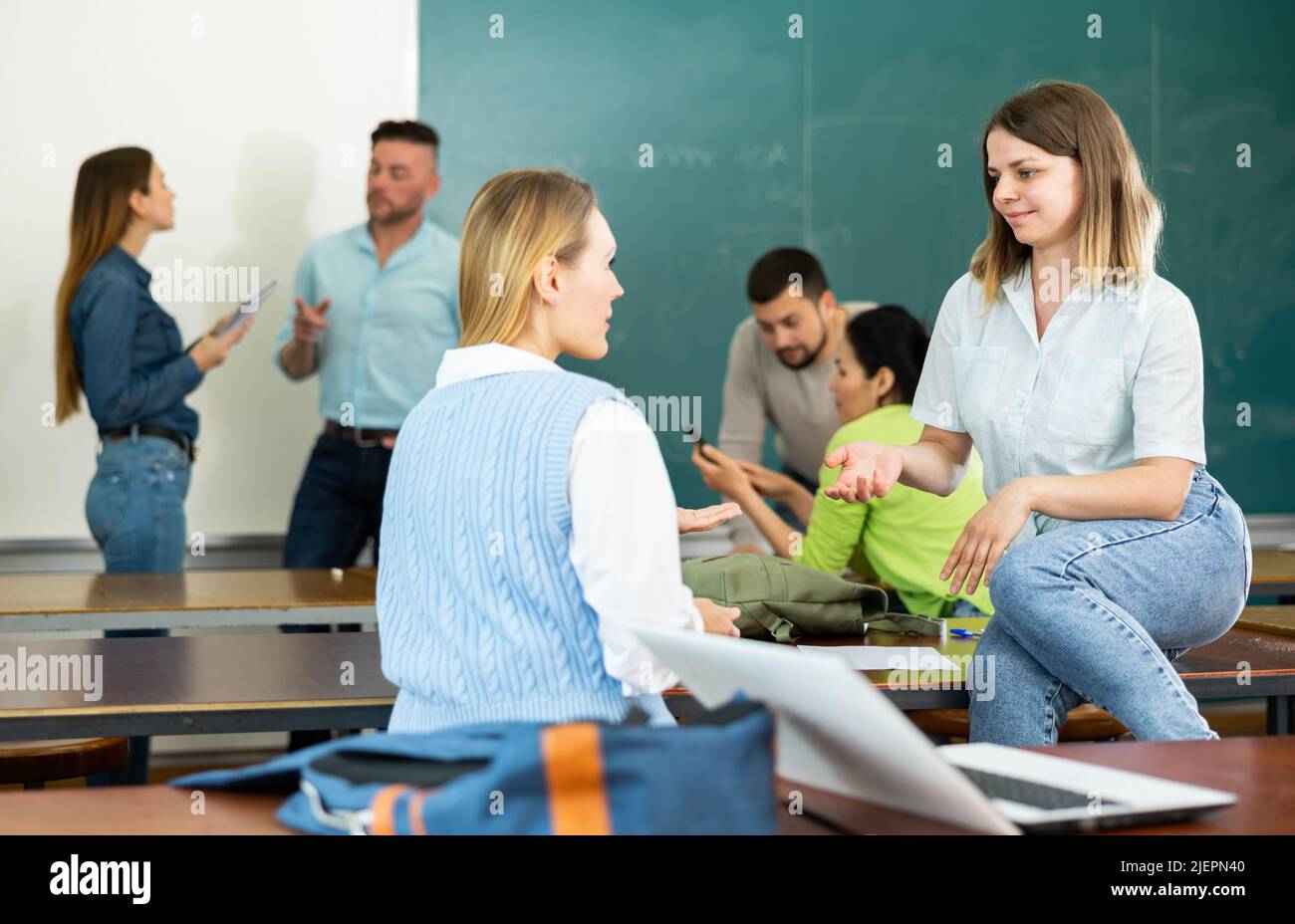Friendly group of students talking in classroom having break between ...