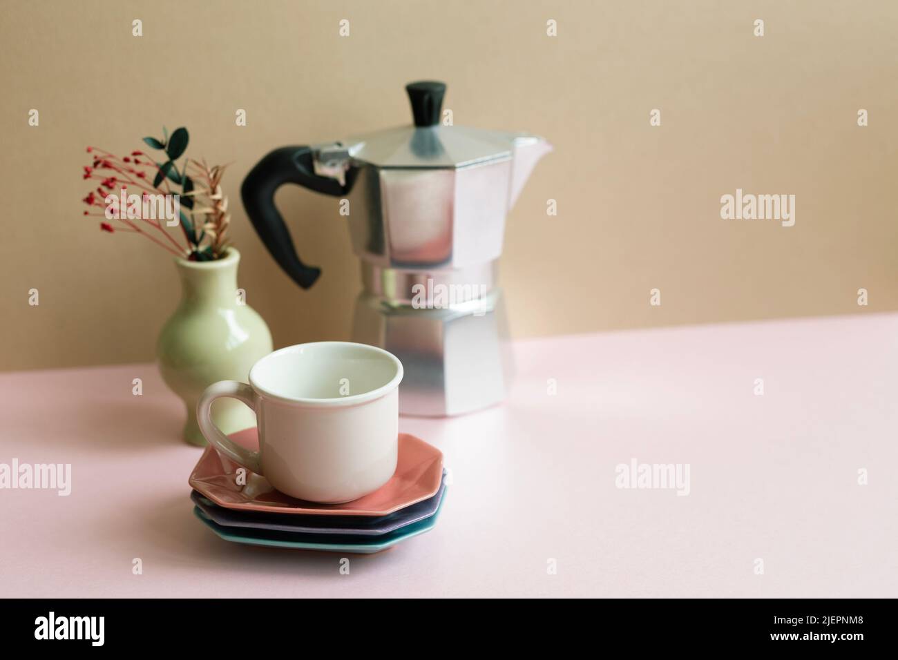 Mocha coffee pot, cup, dry flowers on pink table. beige wall background Stock Photo