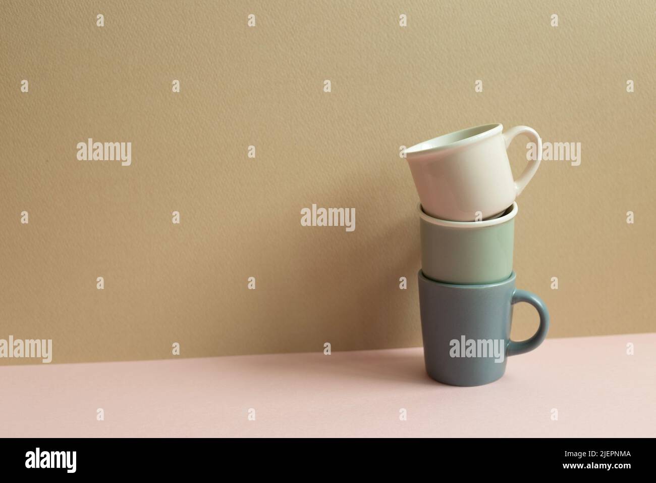 Stack of cups on pink table. beige wall background Stock Photo