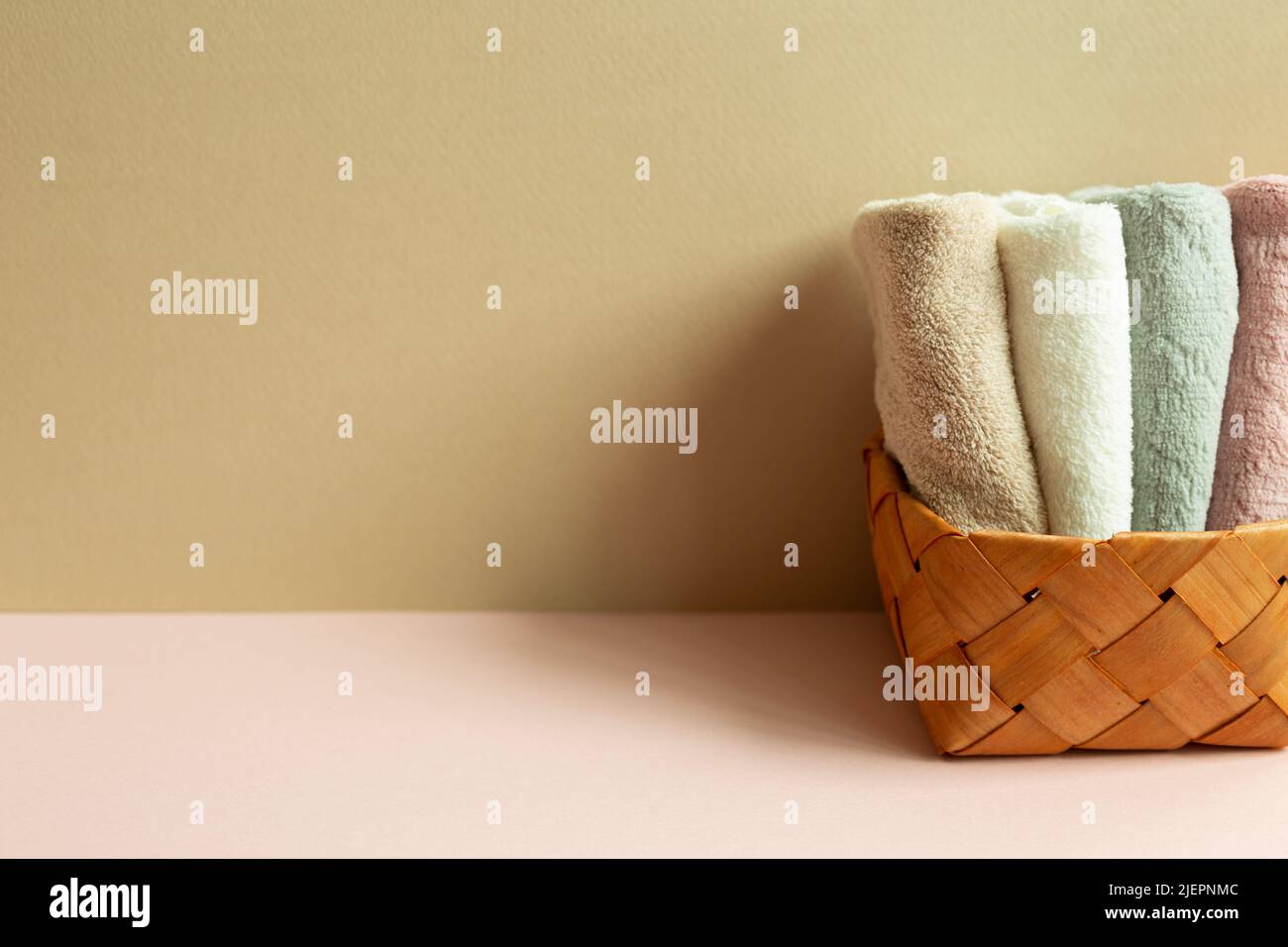 Towels in basket on pink table. beige wall background Stock Photo