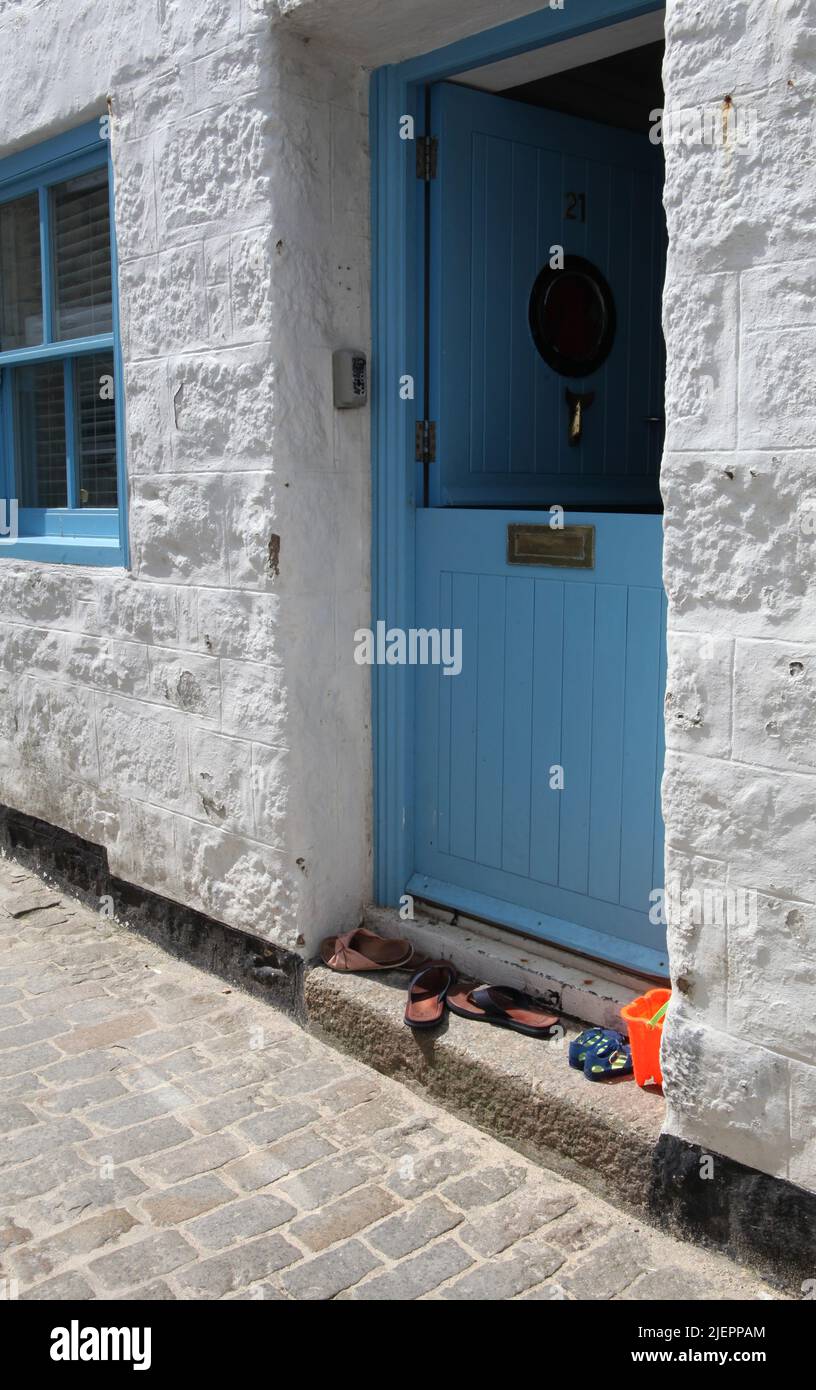 a view of holidaymakers' beach shoes and a bucket on the doorstep of a Cornish cottage in St Ives, Cornwall Stock Photo