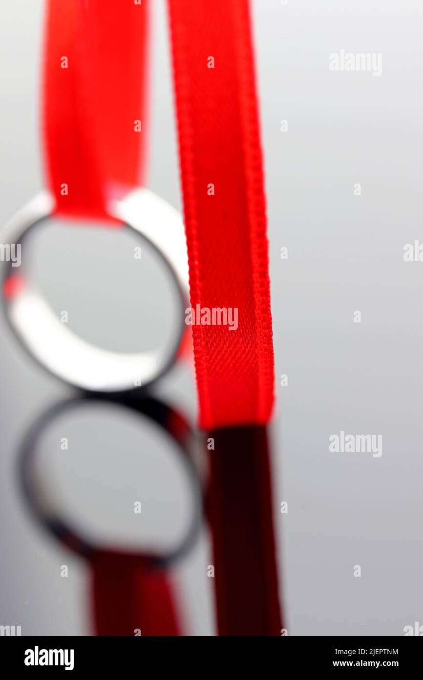 Wedding ring and red ribbon reflection on dark background Stock Photo ...
