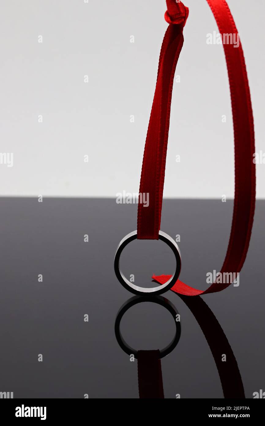 Wedding ring and red ribbon reflection on dark background Stock Photo ...