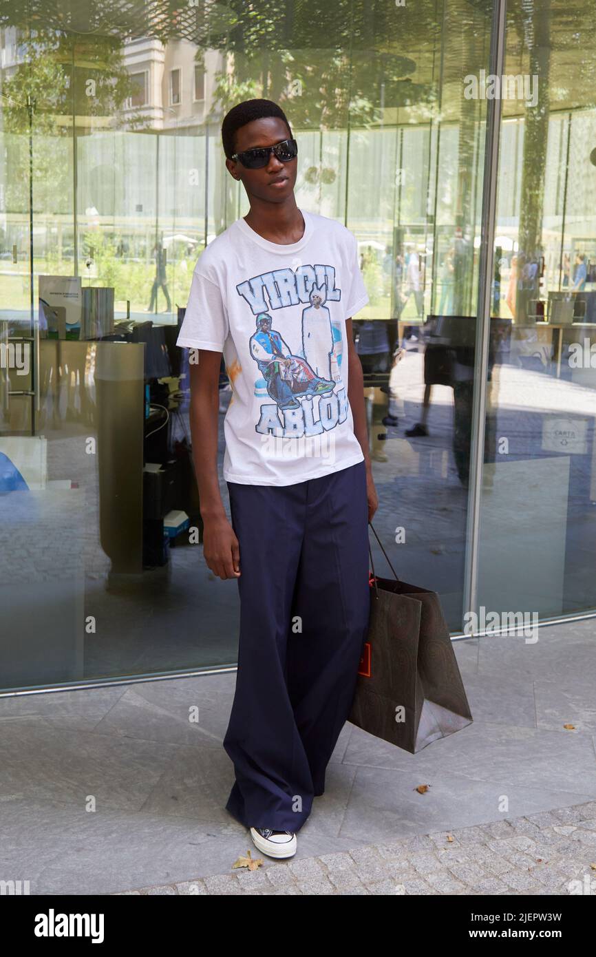 MILAN, ITALY - JUNE 19, 2022: Man with Virgil Abloh white t-shirt and blue trousers before Etro fashion show, Milan Fashion Week street style Stock Photo