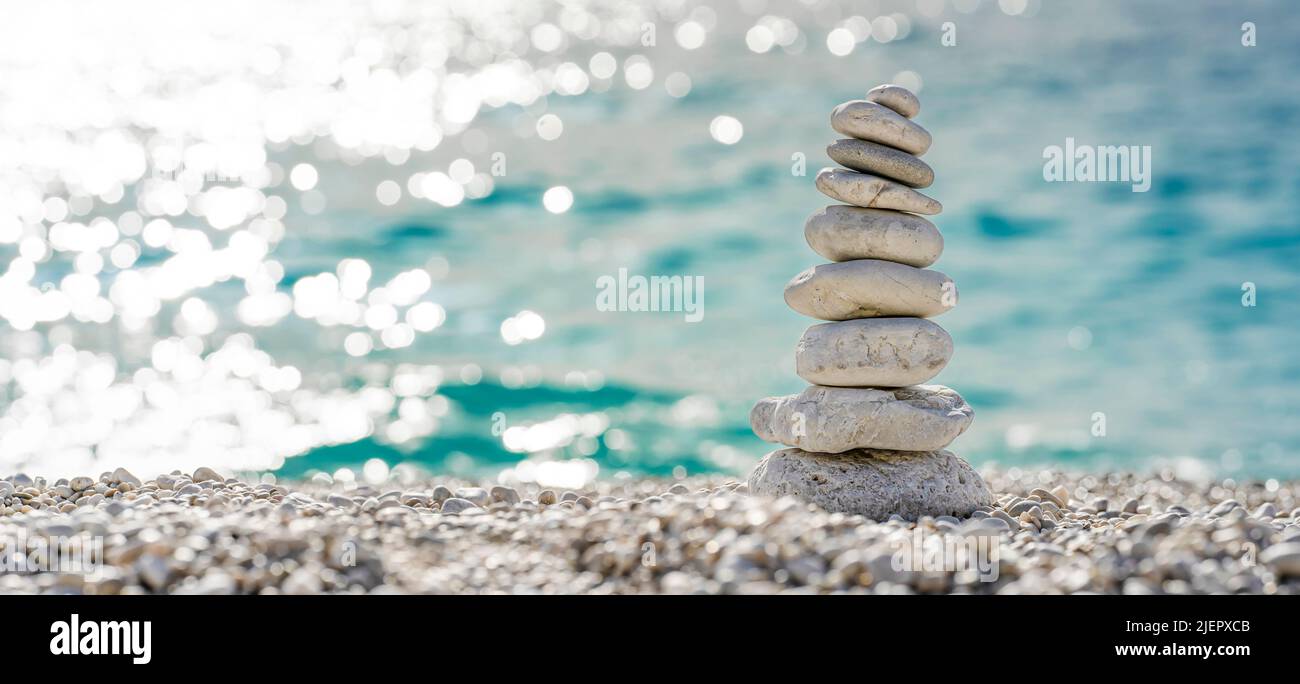 Stacked stones on a beautiful white pebble beach in the Mediterranean Stock Photo