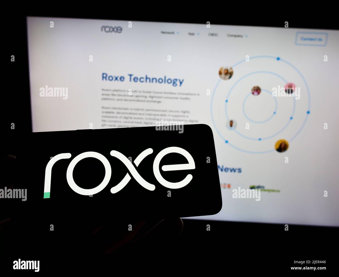 Person holding cellphone with logo of US payment company Roxe Holding Inc. on screen in front of business webpage. Focus on phone display. Stock Photo