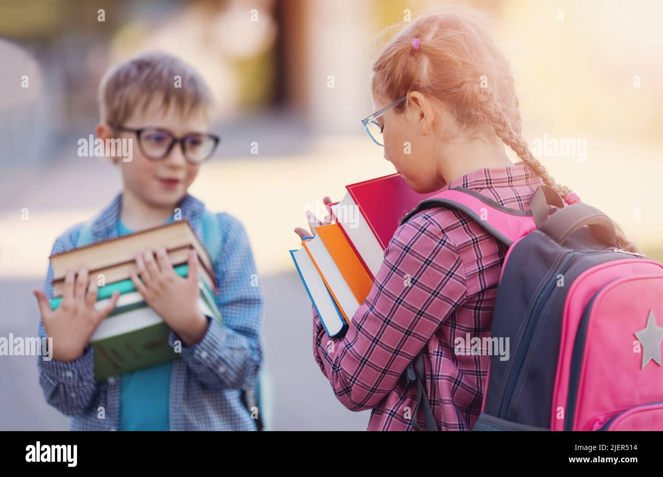 Girl and boy in glasses standing with books in their hands. Stock Photo