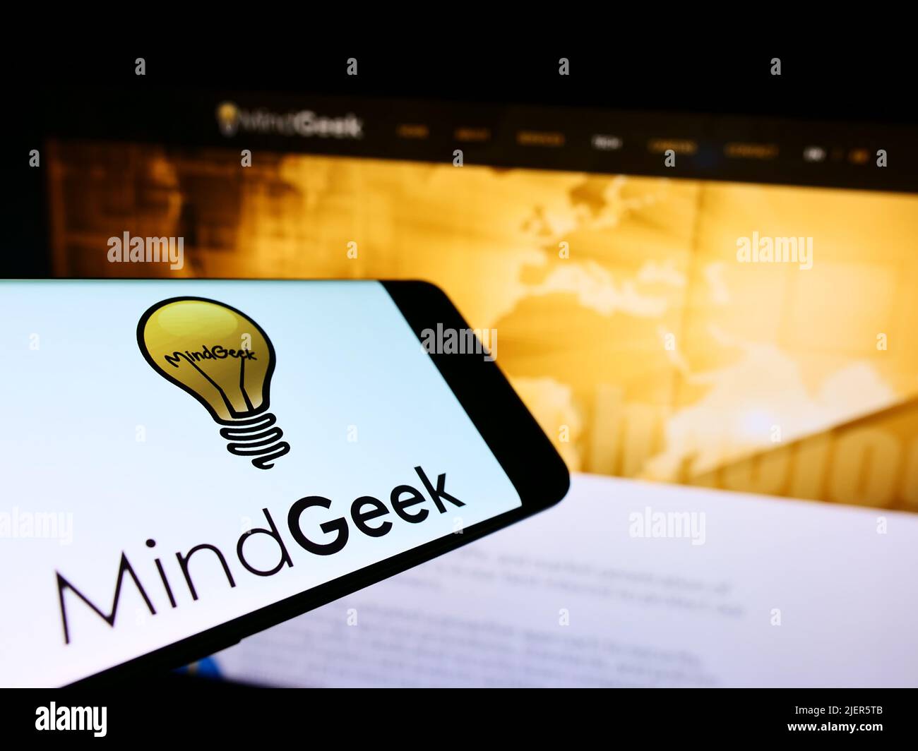 Mobile phone with logo of pornography company MindGeek SARL on screen in front of business website. Focus on center-right of phone display. Stock Photo