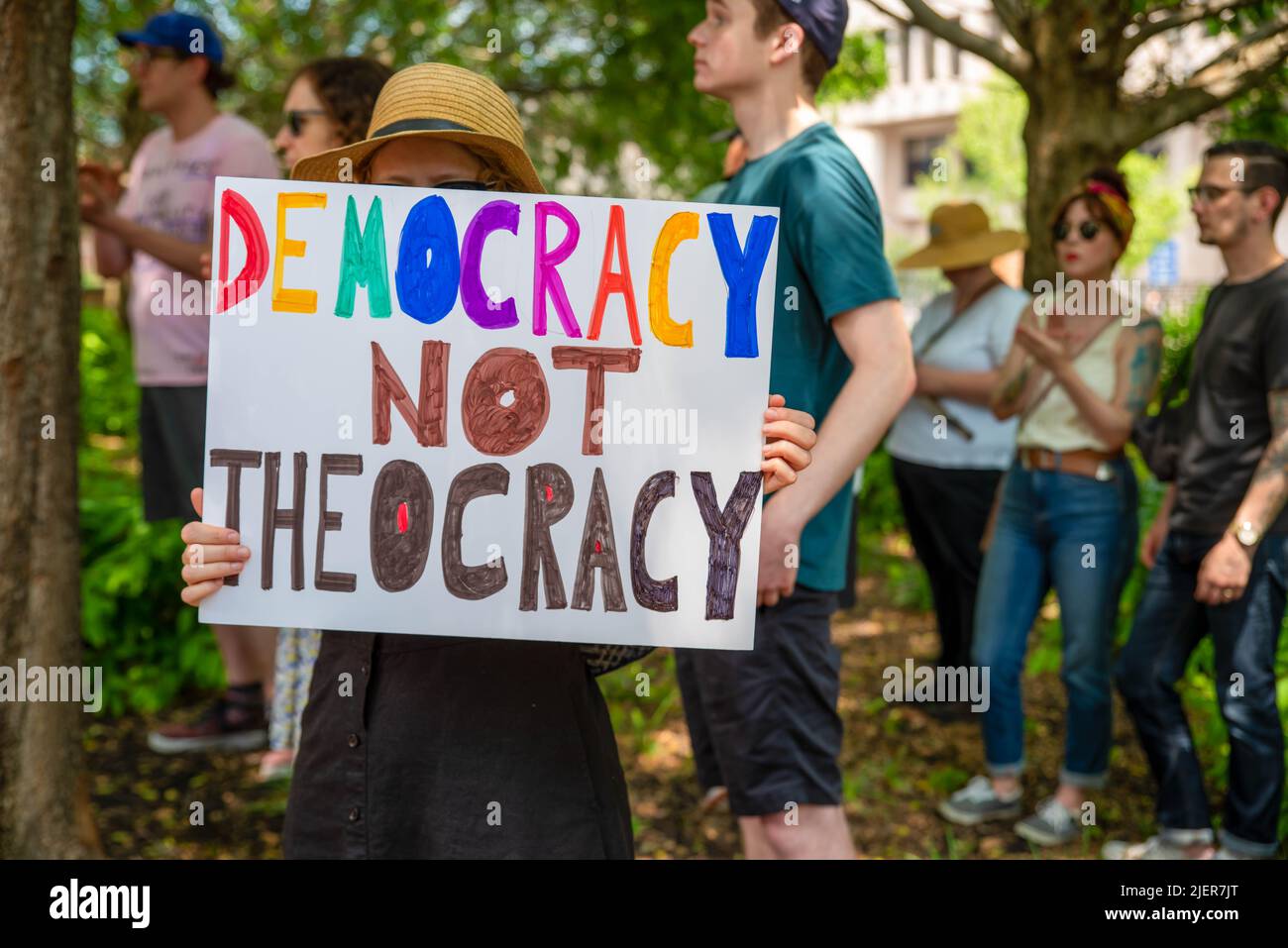 Woman in a crowd at pro-choice rally holds feminist DEMOCRACY NOT THEOCRACY sign Stock Photo
