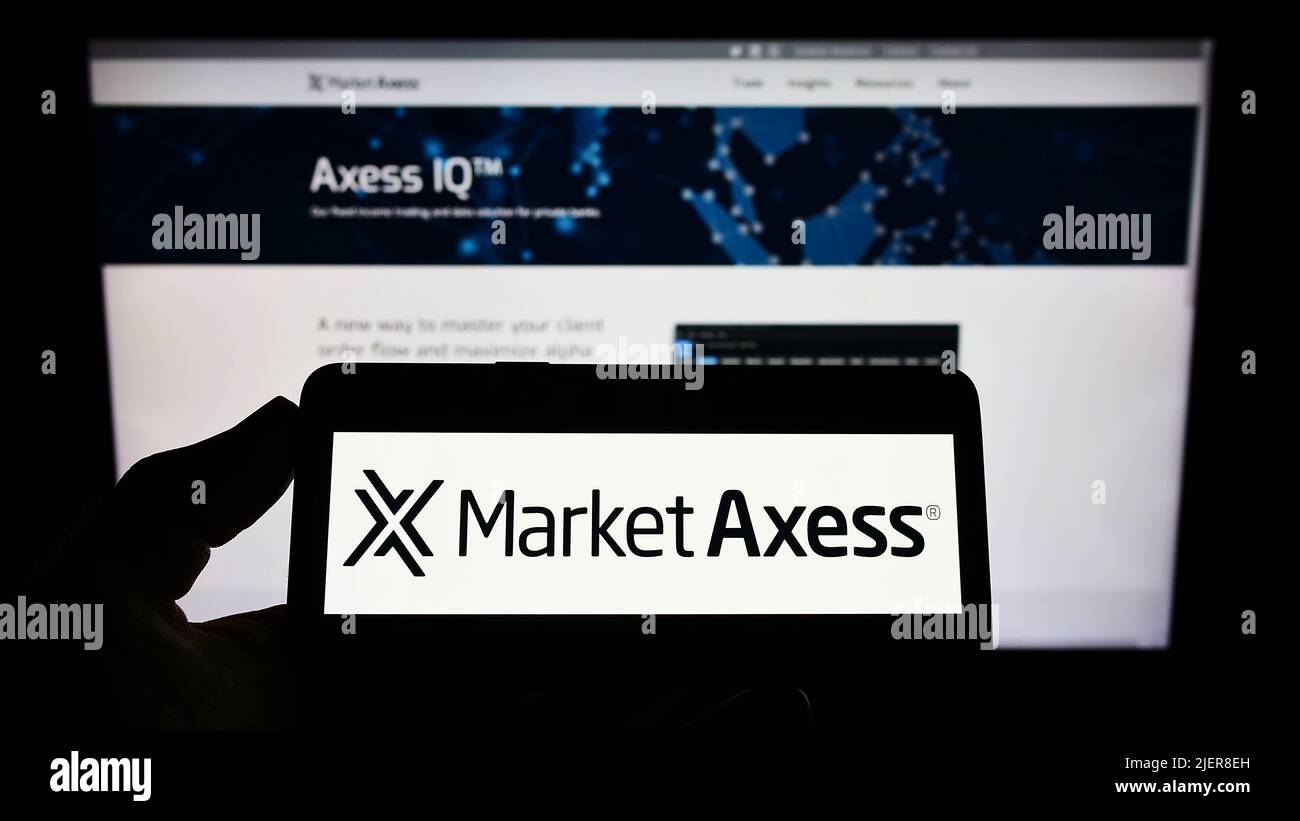 Person holding smartphone with logo of US financial company MarketAxess Holdings Inc. on screen in front of website. Focus on phone display. Stock Photo