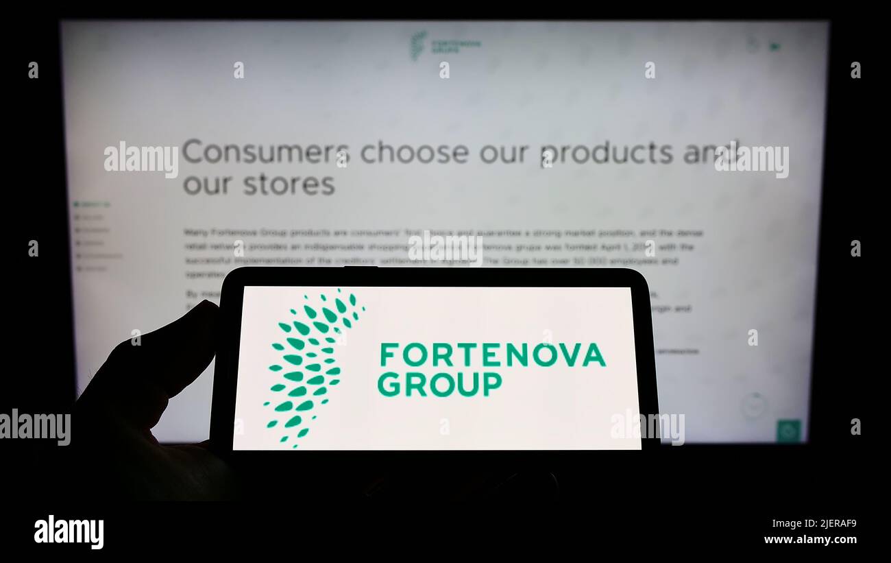Person holding smartphone with logo of Croatian conglomerate Fortenova Group on screen in front of website. Focus on phone display. Stock Photo
