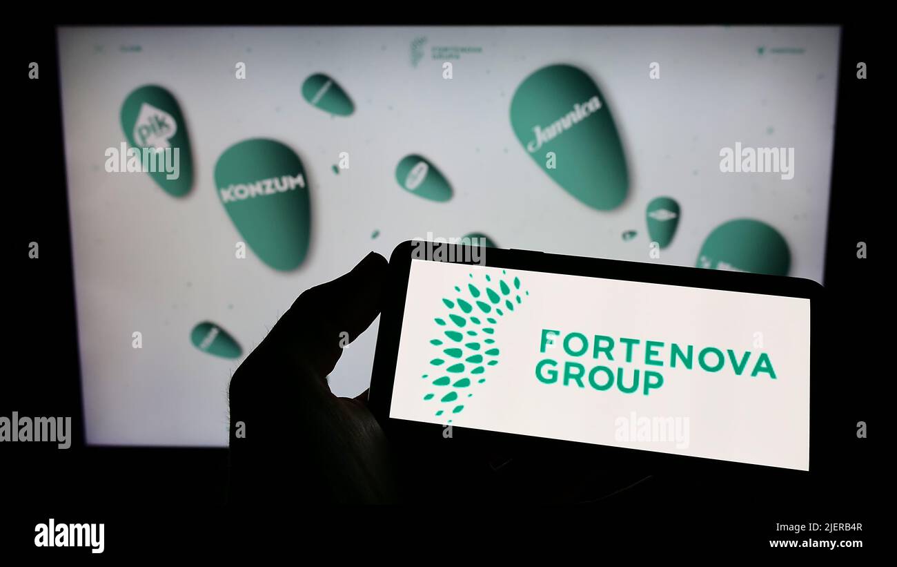 Person holding cellphone with logo of Croatian conglomerate Fortenova Group on screen in front of business webpage. Focus on phone display. Stock Photo
