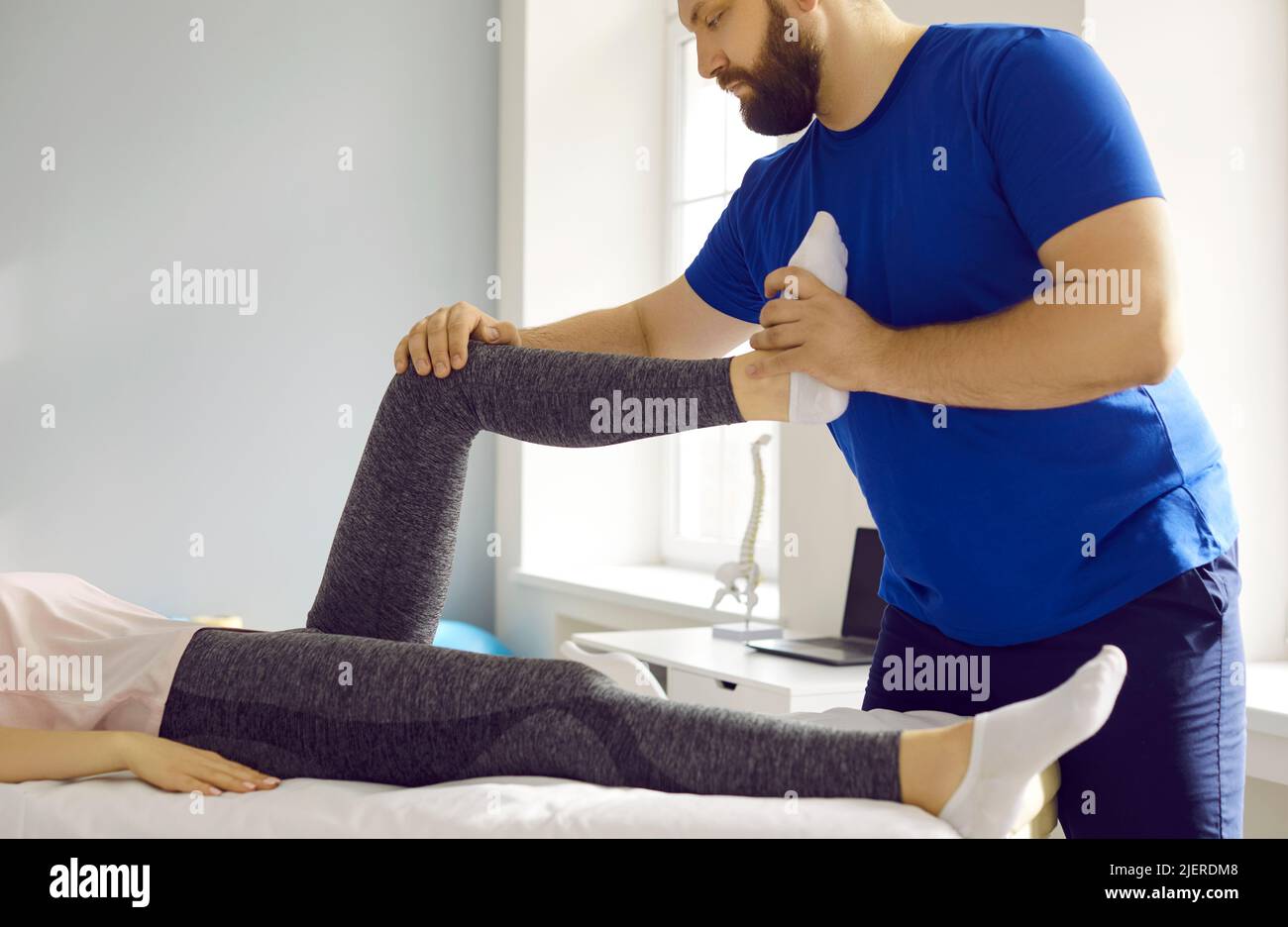 Pprofessional male masseur therapist kneads female patient's leg in physiotherapy clinic. Stock Photo