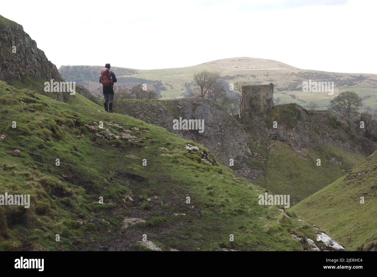 Man Looking at Peveril/Castleton Castle from the Peak Cavern Gorge on the Limestone Way in Castleton, Derbyshire, Peak District National Park. UK. Stock Photo