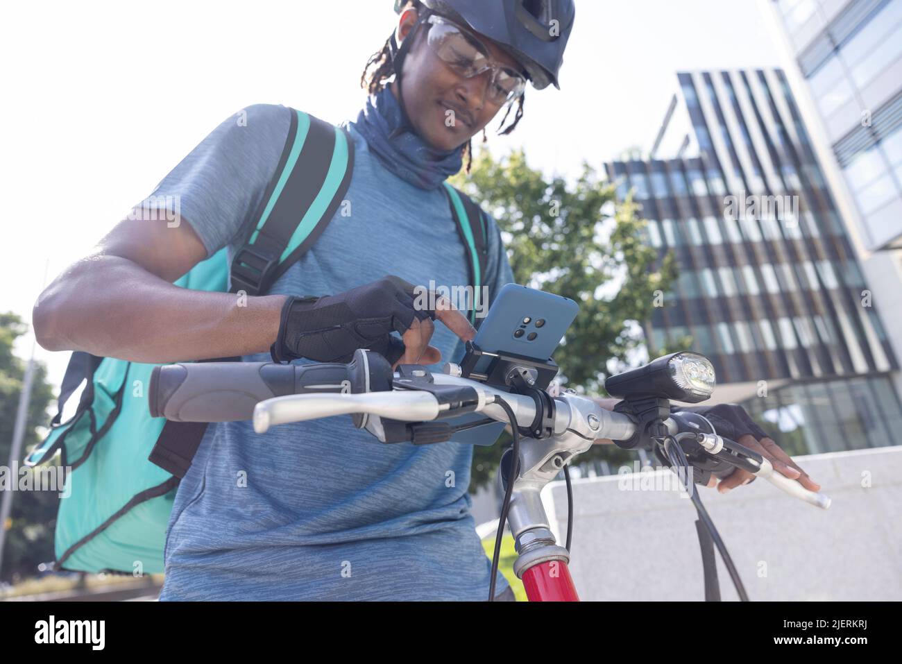 Courier On Bike Delivering Takeaway Food In City Checking Directions And Order Details On Mobile Phone Stock Photo