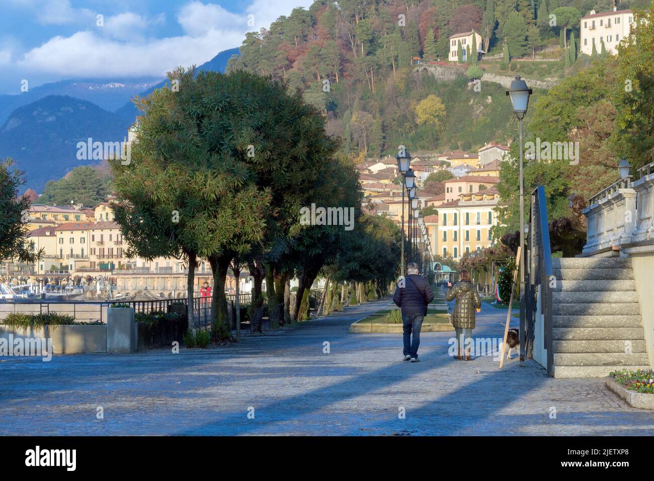 Bellagio, Italy, November 2021. A man and a woman walk their dog along the Bellagio promenade on the shores of Lake Como. Walks along the lake. Journe Stock Photo