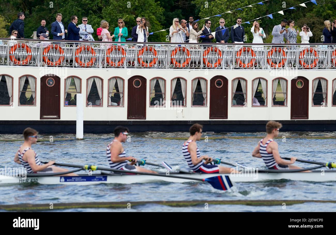 People on the New Orleans Paddle Steamer Boat look on as a rowing crew from Hereford Rowing club compete on the opening day of the 2022 Henley Royal Regatta alongside the River Thames. Picture date: Tuesday June 28, 2022. Stock Photo