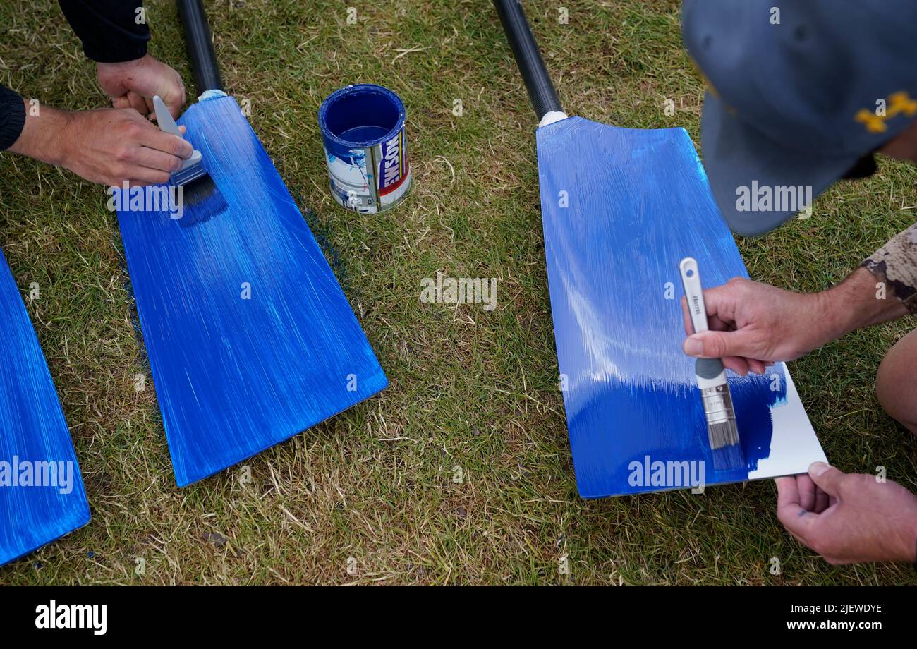 People paint rowing blades on the opening day of the 2022 Henley Royal Regatta alongside the River Thames. Picture date: Tuesday June 28, 2022. Stock Photo