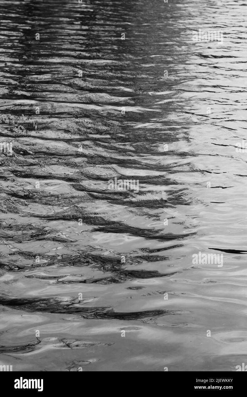 Waves and ripples wandering thru the surface of the water in black and