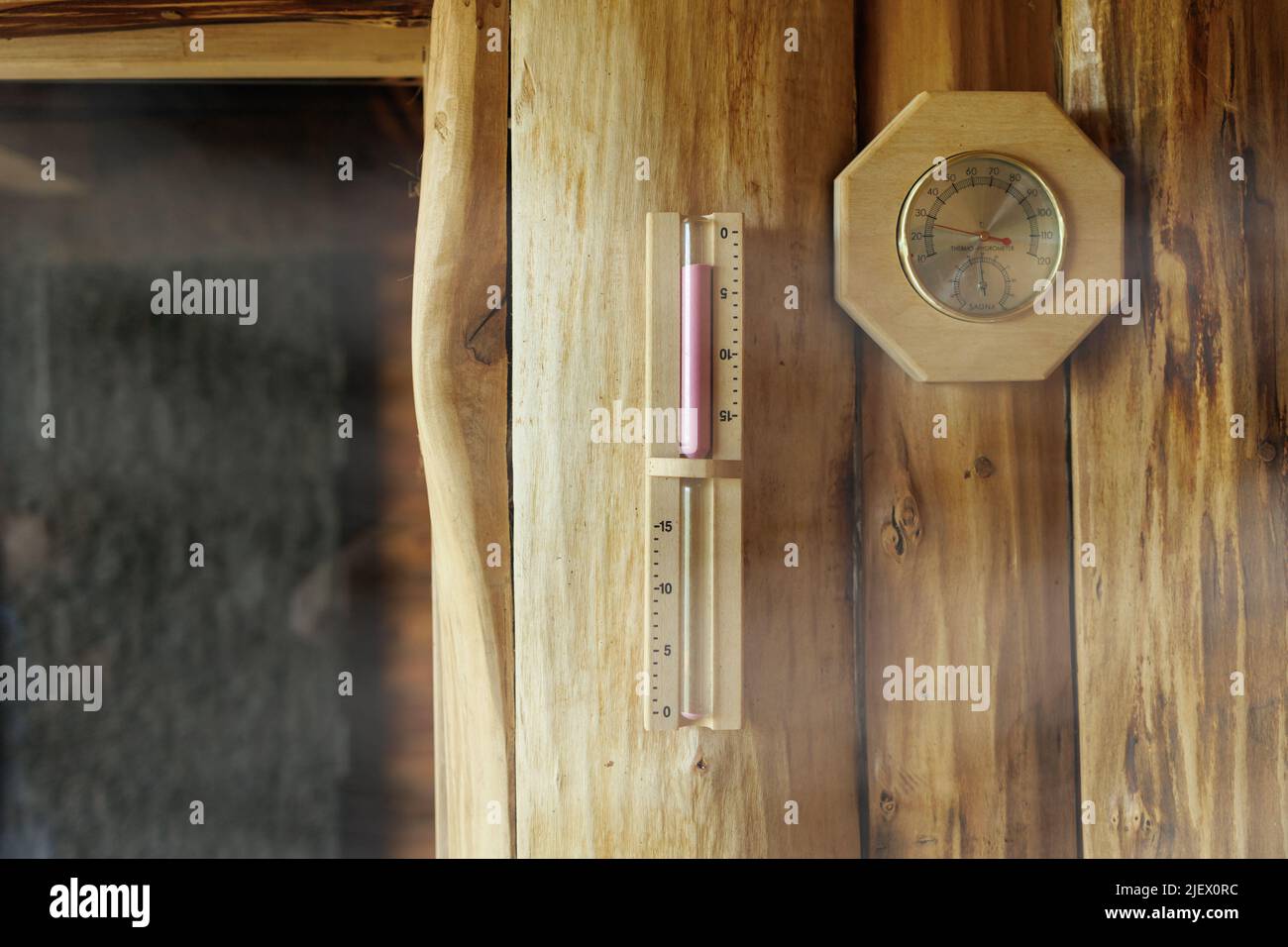 Sand timer and thermometer with hygrometer hanging on the wooden wall