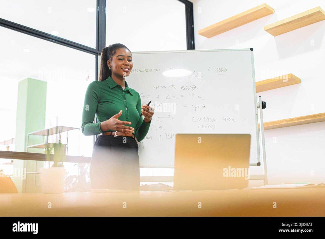 African-Ameriacn young woman is conducts online webinars, online classes, online presentation. Multiracial showing something on a flip-chart in a office classroom to virtual audience on a laptop Stock Photo