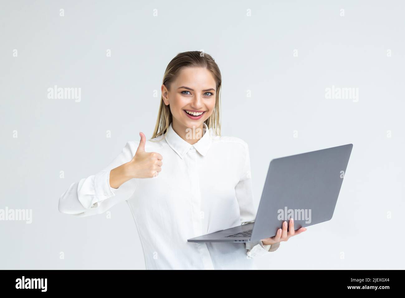 Happy young business woman showing thumbs up against white background ...