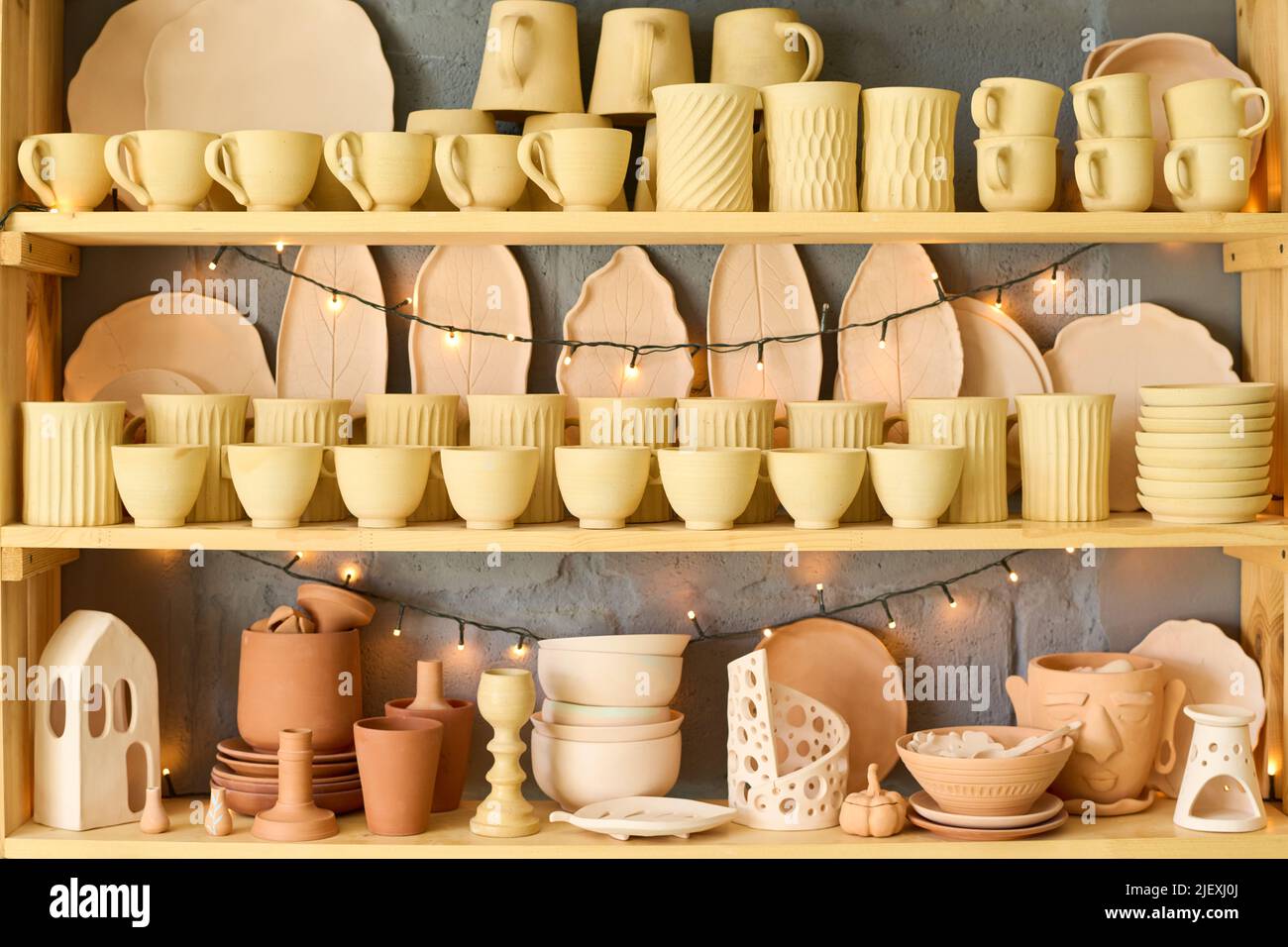 Large display with variety of handmade earthenware and clay items such as mugs, bowls, pots and plates for sale in small shop of handcraft Stock Photo
