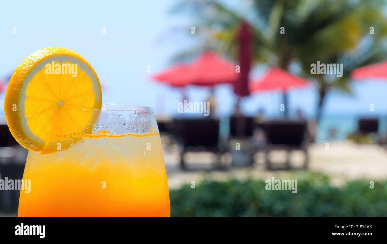 Mocktail drink with orange slice standing in poolside beach bar with