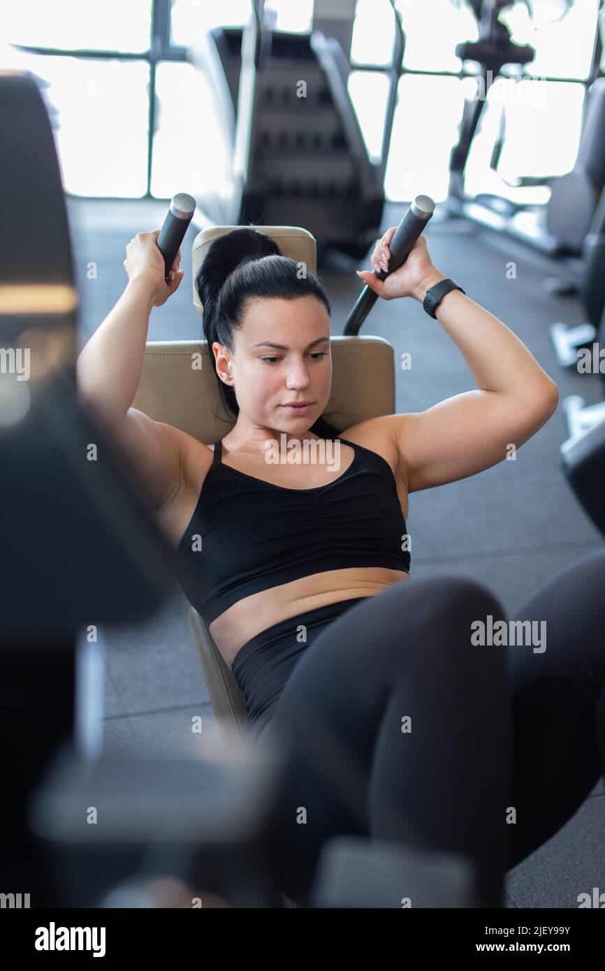 Young Caucasian woman in gym doing crunches on machine Stock Photo