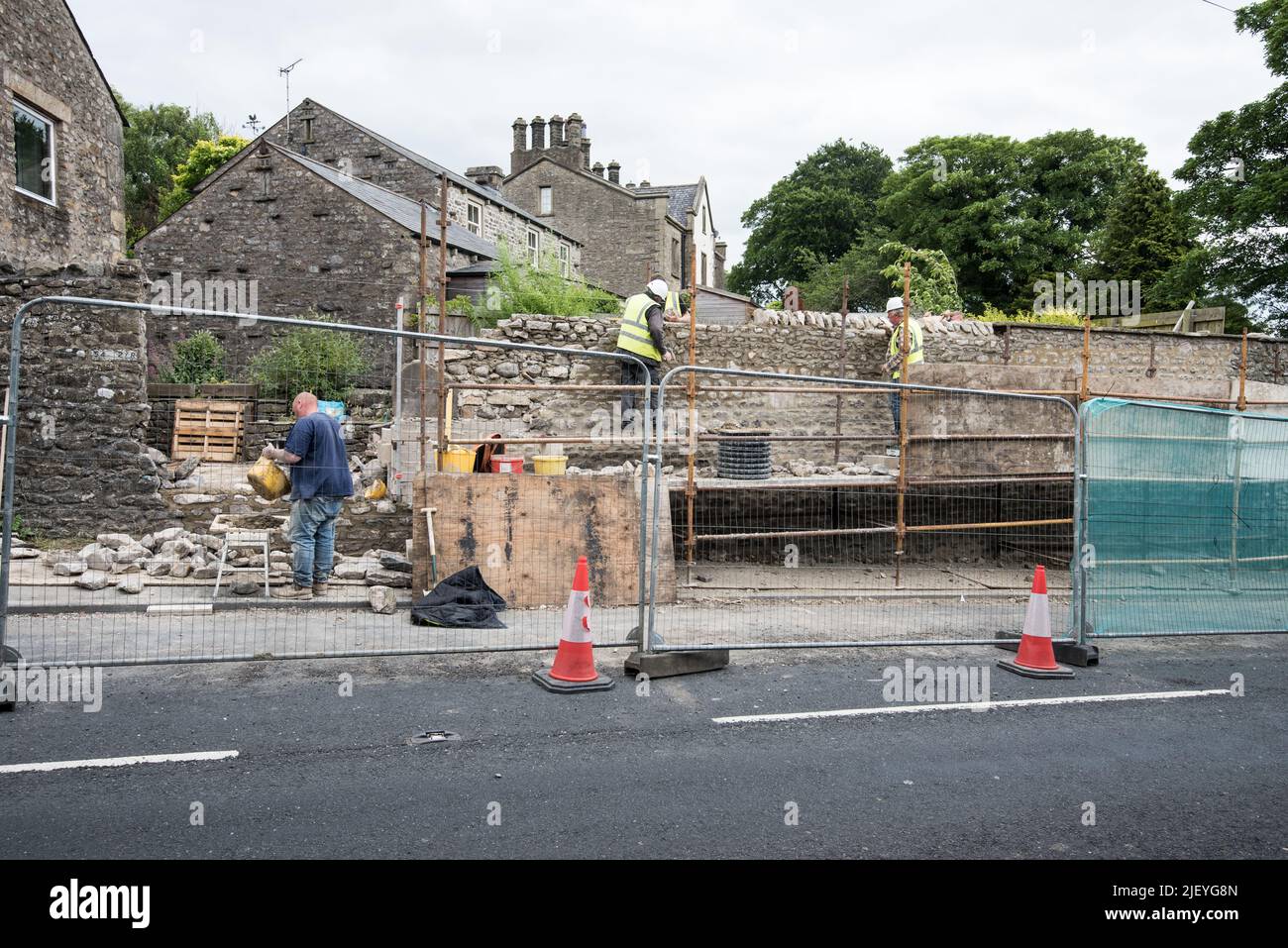 Coping stone layer being added to wall at Kayley Hill, Long Preston 28/6 22 .Also connecting up up to the older.lef-sidet,(non block-backed) section. Stock Photo