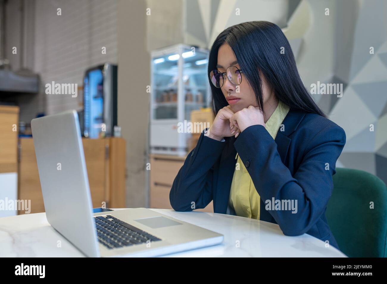 Woman looking at laptop sitting working in office Stock Photo
