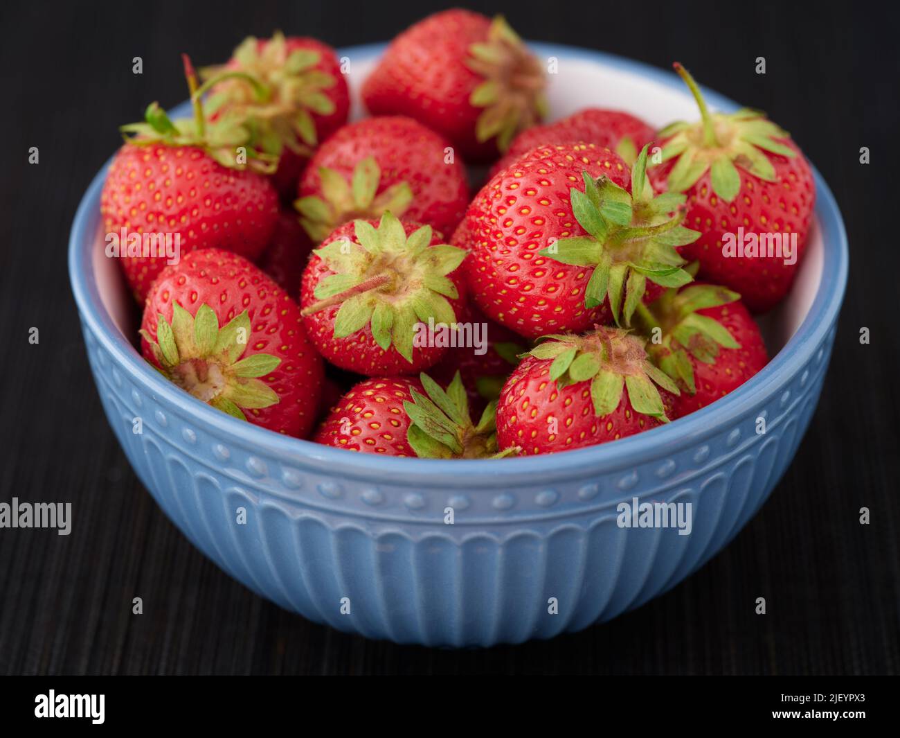 Fresh organic strawberries in a bowl. Low key. Close up. Stock Photo