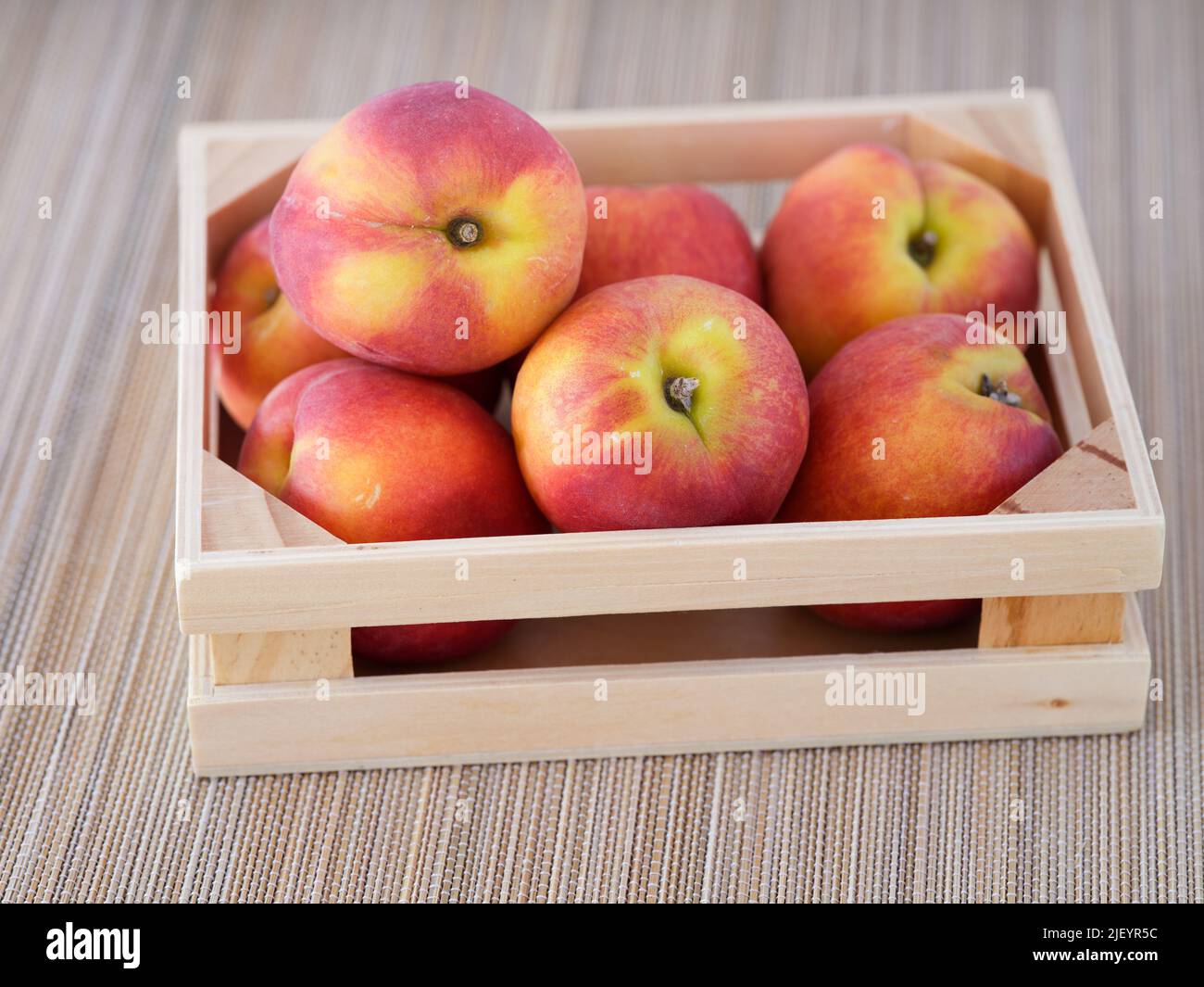 Freshly harvested peaches in a small wooden crate. Close up. Stock Photo