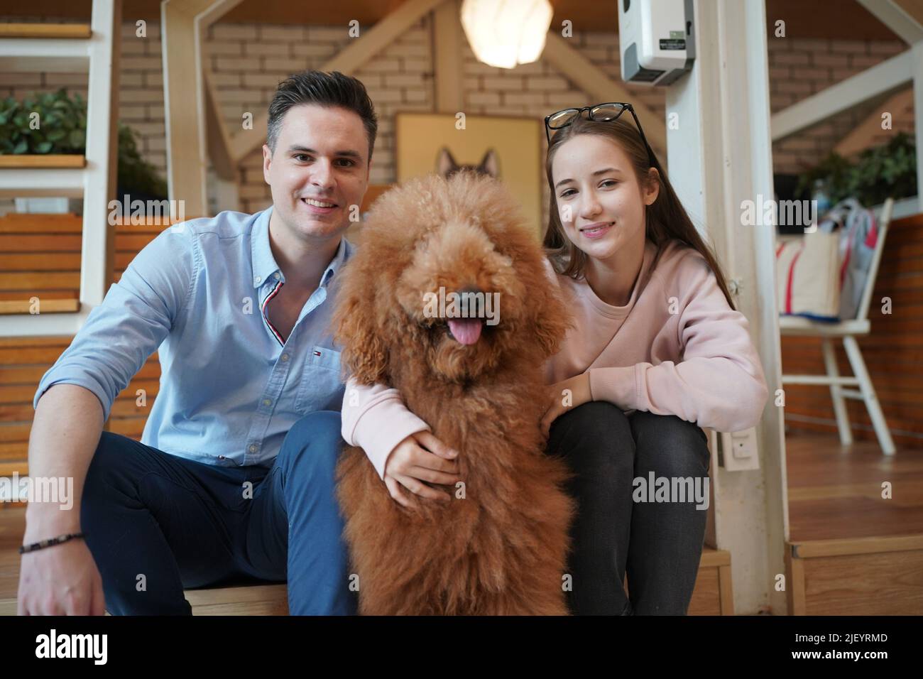 Man and girl with his pet dog playing on the floor. Happy dog, happy guy with dog. Stock Photo