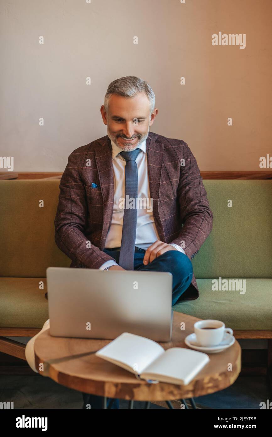 Man sitting smiling at laptop screen Stock Photo - Alamy