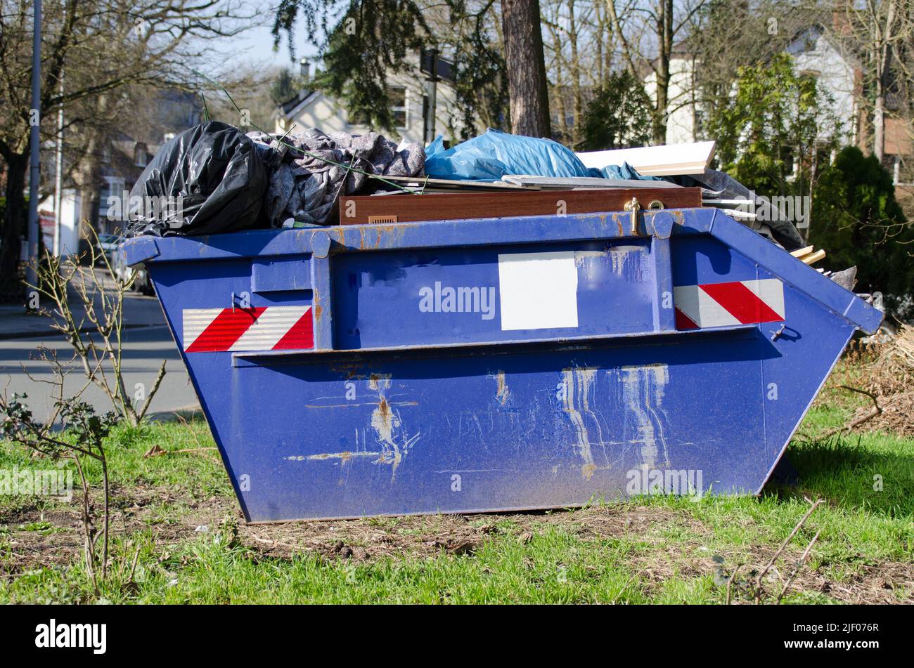 Blue container or dumpster with bulky waste standing on a lawn in a residential area Stock Photo