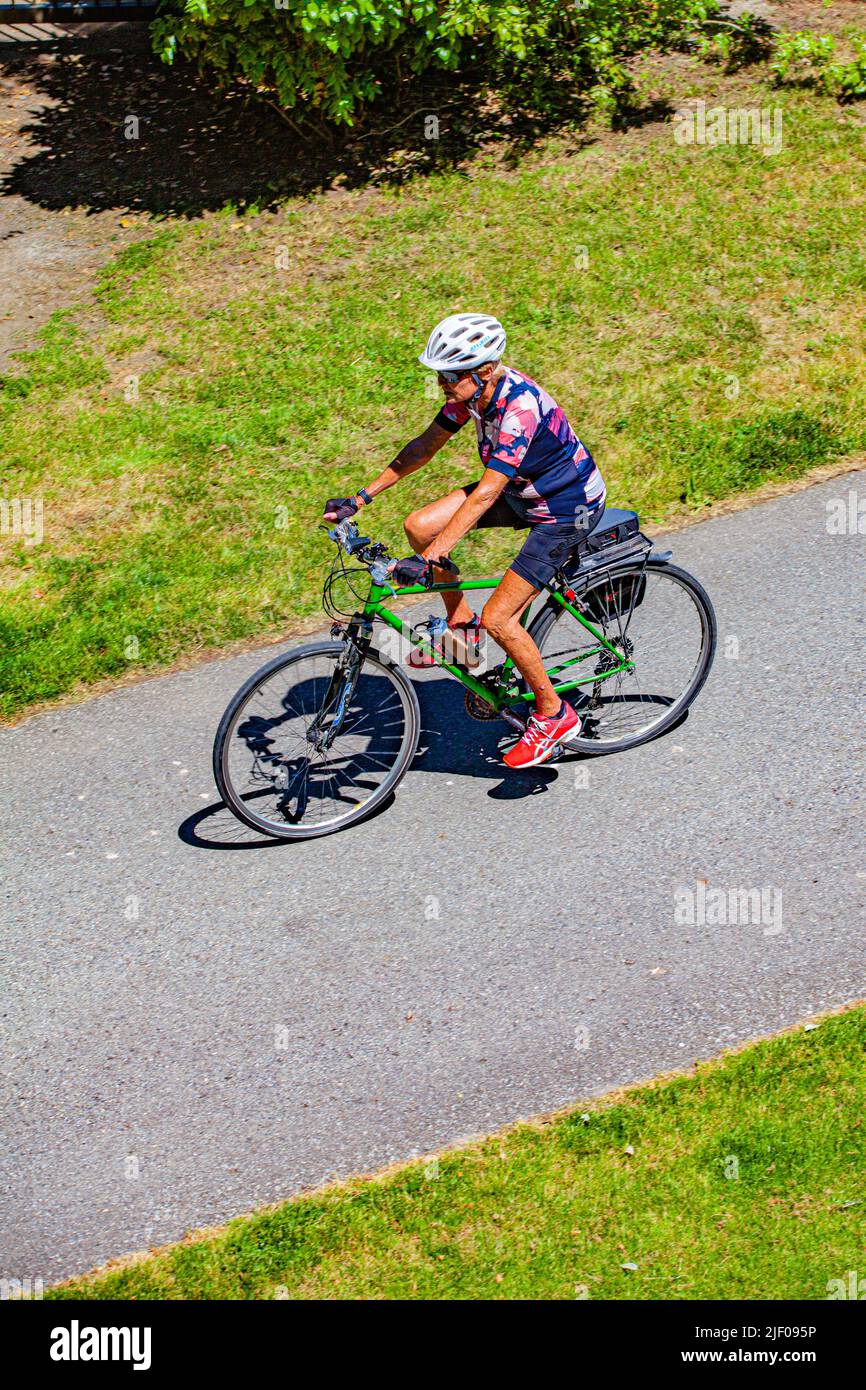 An older person riding their bicycle along a bikeway in British Columbia Canada Stock Photo