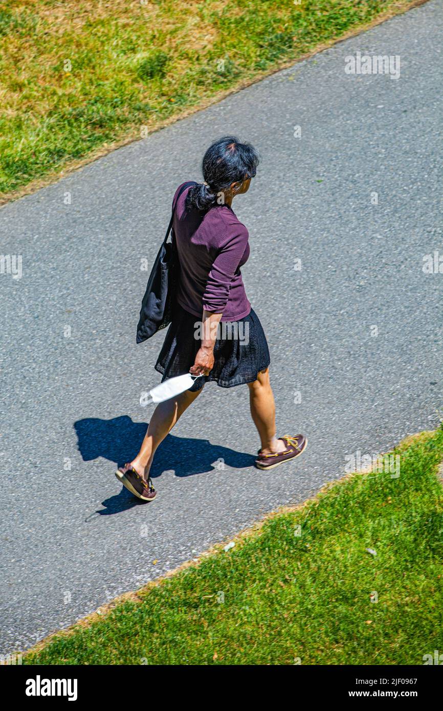 Woman carrying her Covid face mask while walking Stock Photo
