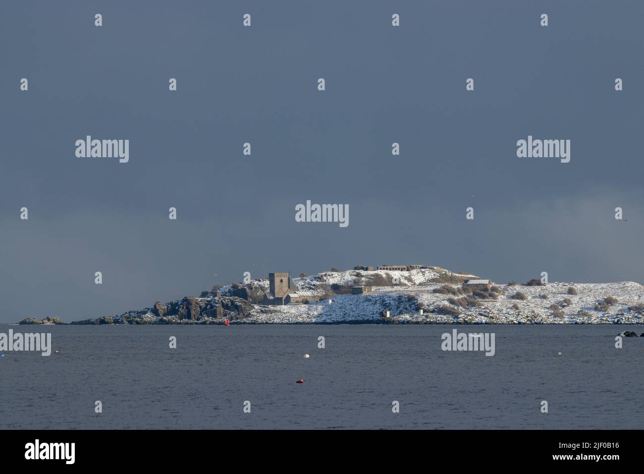 Inchcolm Abbey covered in snow seen from Dalgety Bay, Fife. Stock Photo