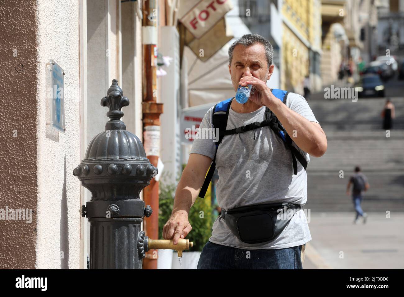 Man drinking the water from the city fountain during the first heat ...