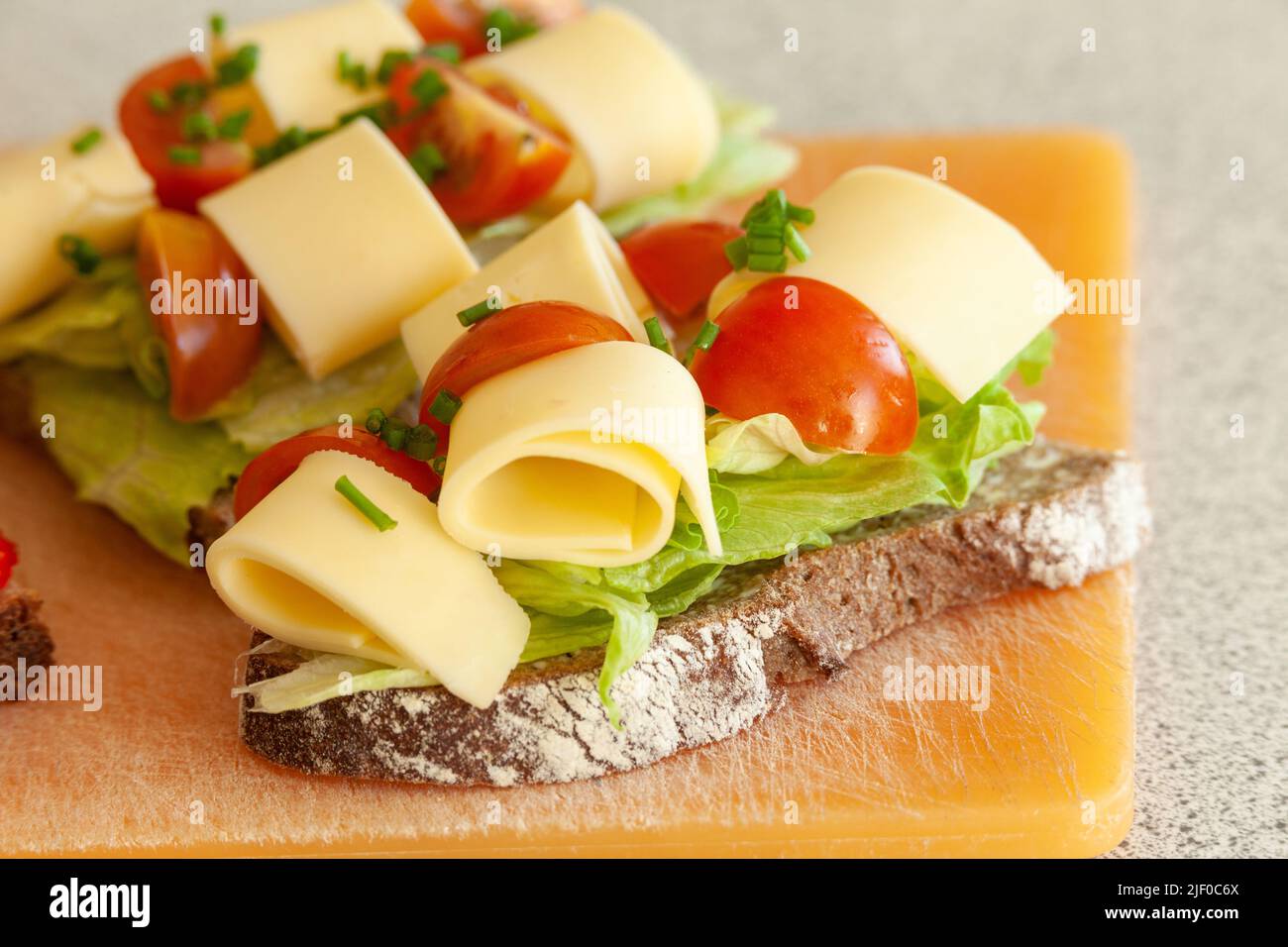 Danish style cheese, lettuce and cherry tomato open sandwich Stock