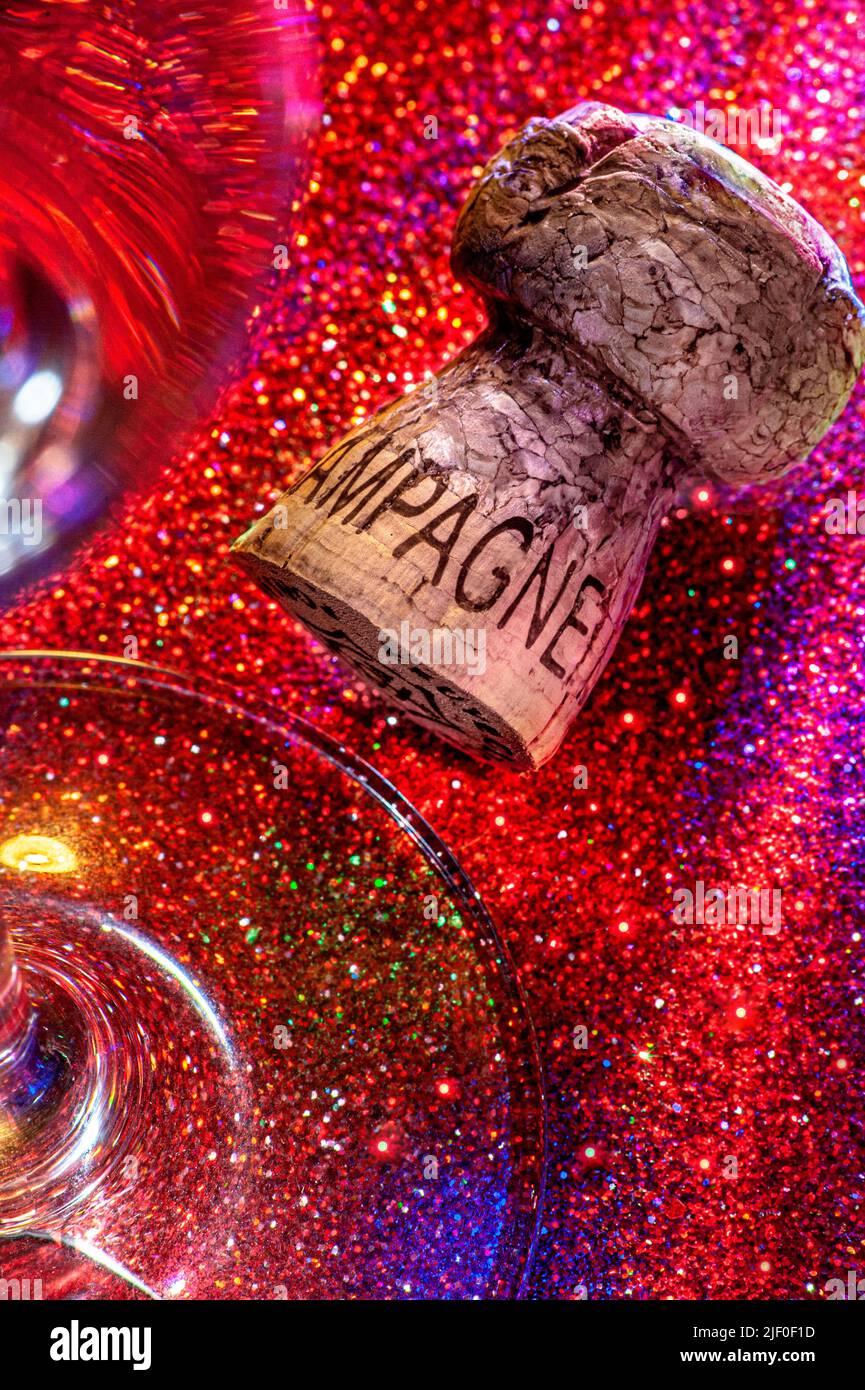 Champagne cork and glass on sparkling nightclub party table surface with multicolor lighting, celebration fun party, disco club clubbing concept Stock Photo