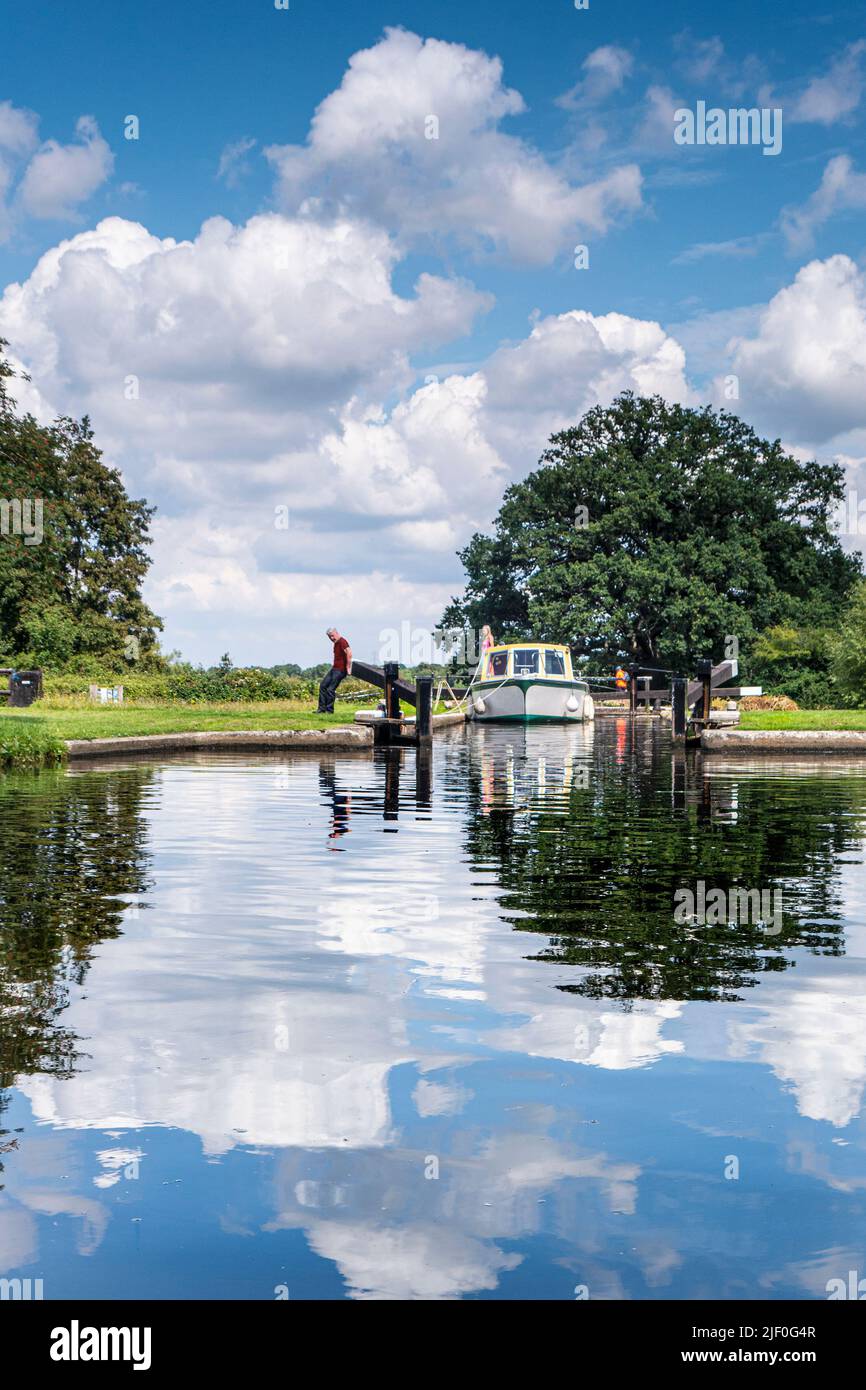 Boating holiday cruise vacation River Wey Lock manual locking summer, with cabin cruiser exiting Papercourt Lock cruising upstream River Wey Surrey Stock Photo